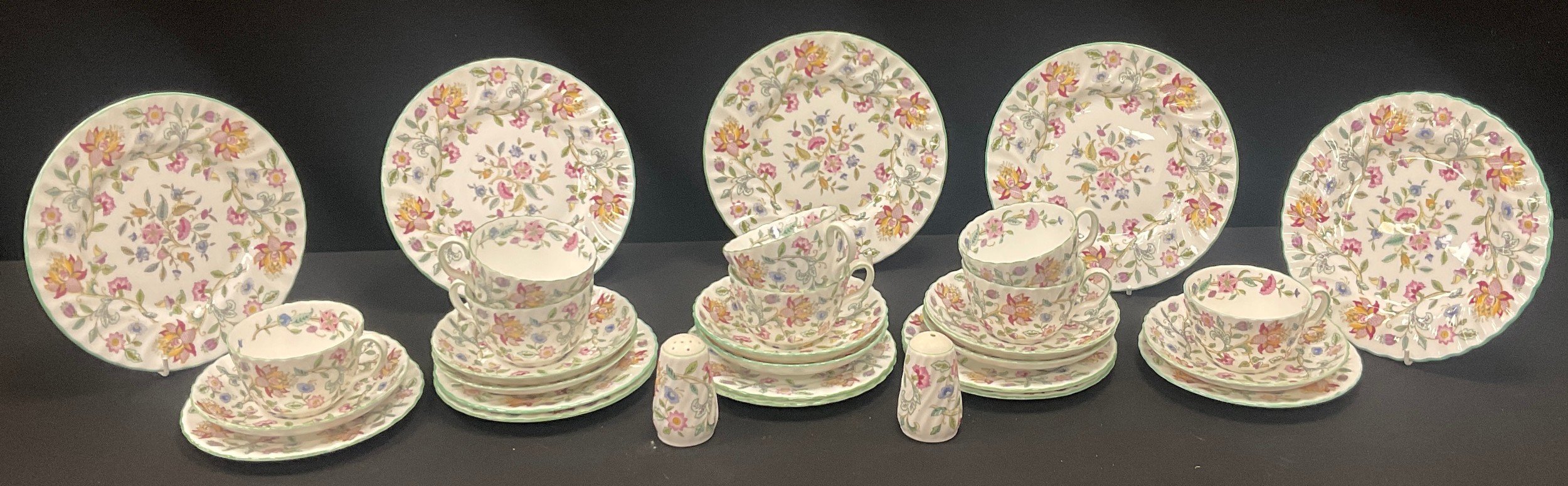 Minton Haddon Hall tea service with cups, saucers, plates, and floral decoration arranged across a table
