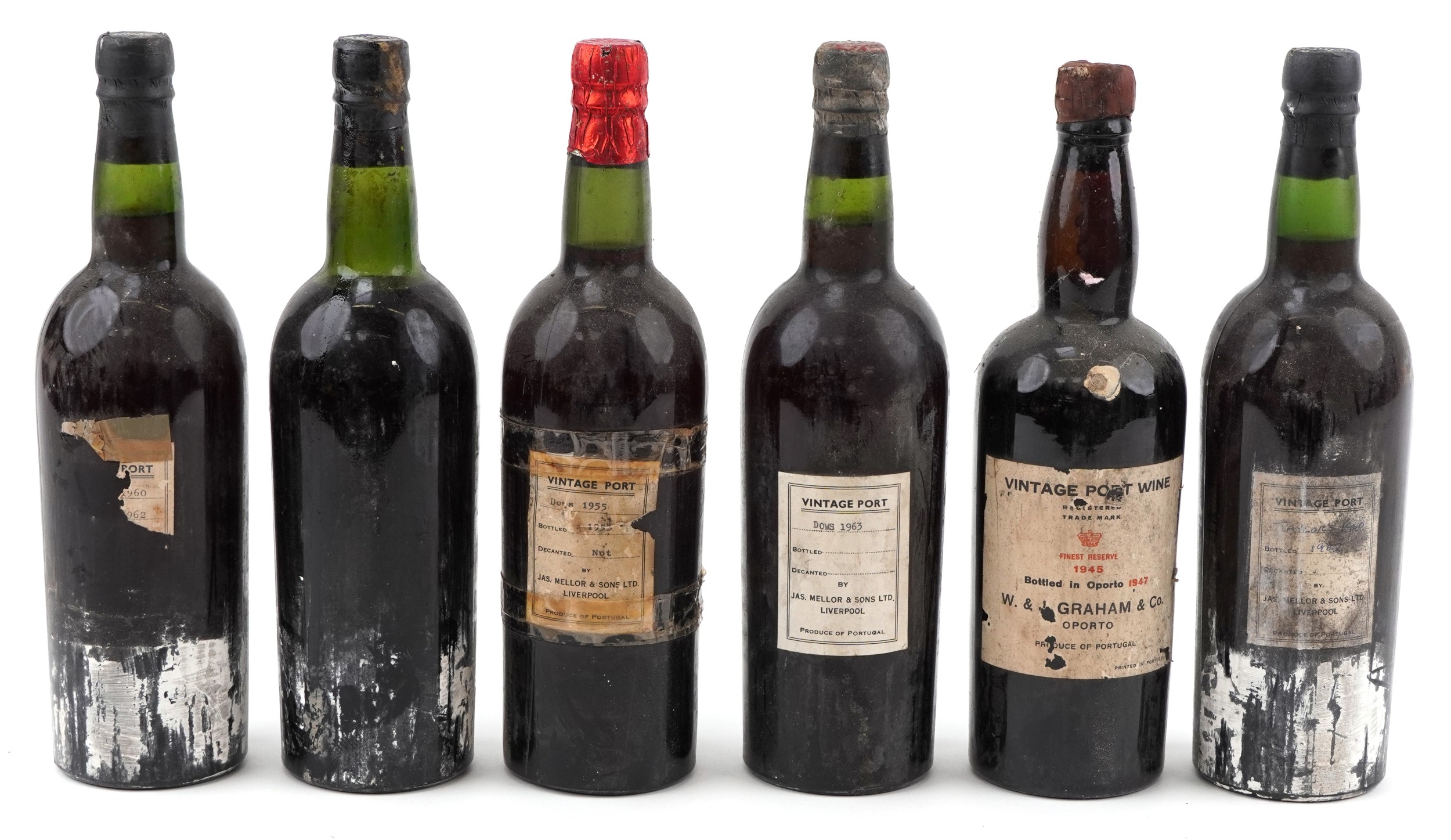 Six dusty vintage port bottles with mixed capsule colours, scuffed glass, replacement labels, and one prominently labelled W and J Graham 1945 bottle