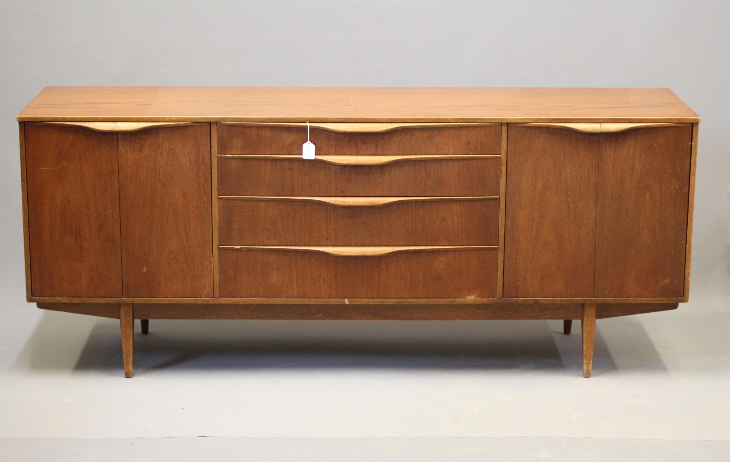 Mid-century teak sideboard by Sutcliffe of Todmorden with four central drawers, paired cupboards, lip handles, and tapering legs