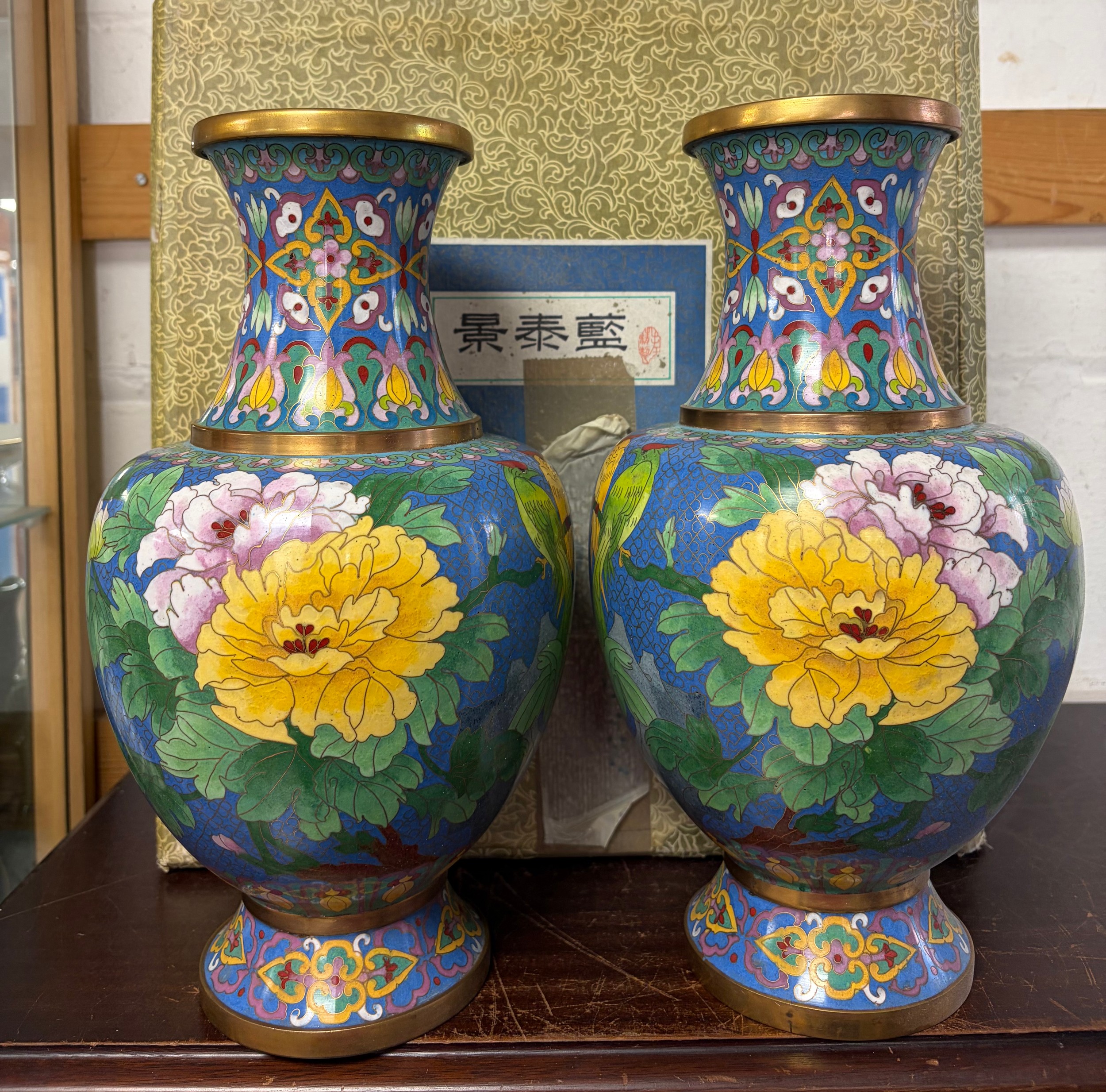 Pair of Chinese cloisonne enamel vases with floral and bird decoration on a blue ground