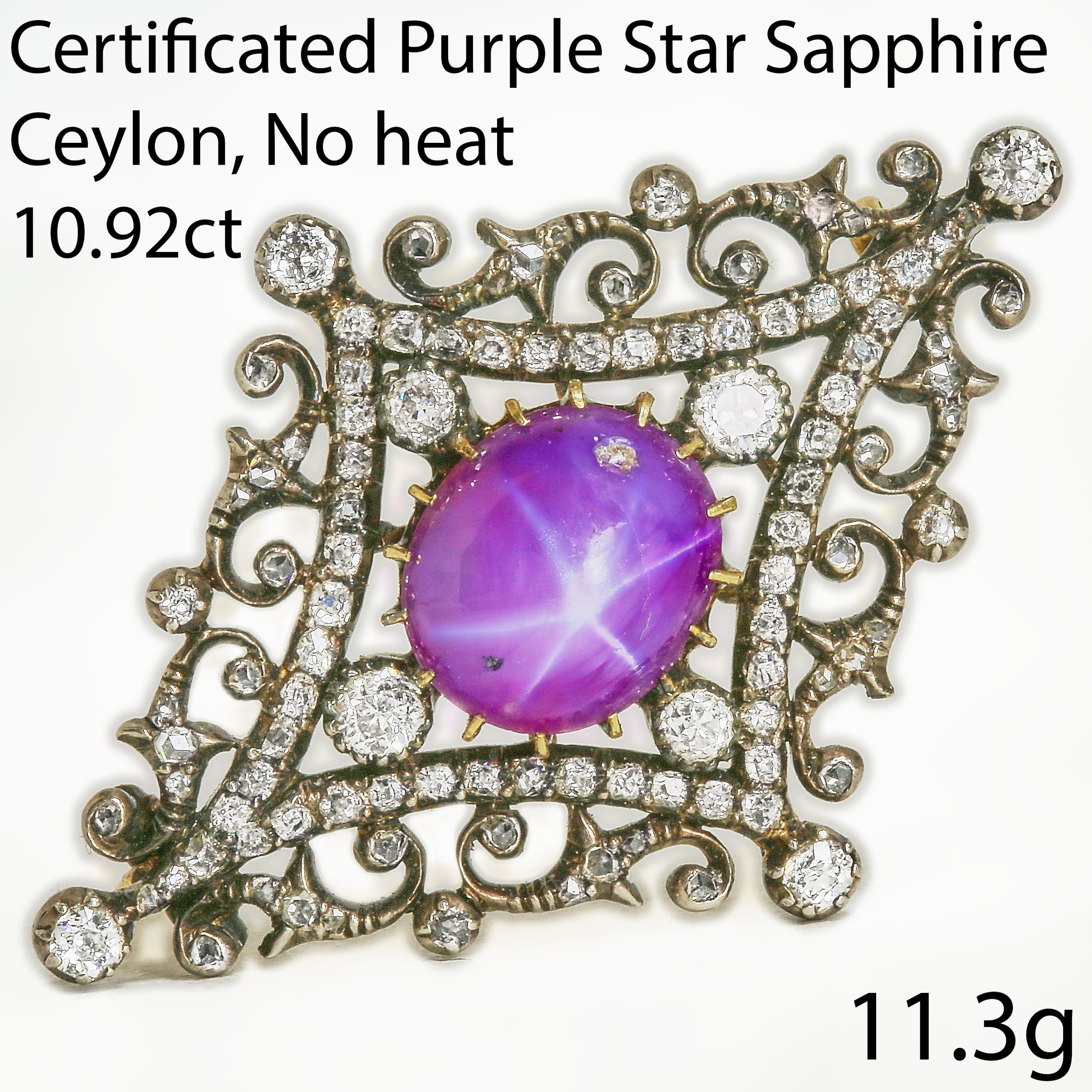 Victorian purple star sapphire and diamond brooch in an ornate openwork setting with scrolling foliate motifs