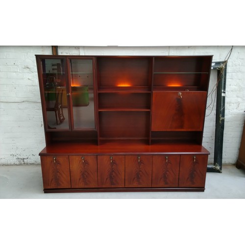 Mid-century Meredew modular display unit with glazed cabinet doors, open shelving, drop-down cocktail compartment, integrated lighting, and a long cupboard base