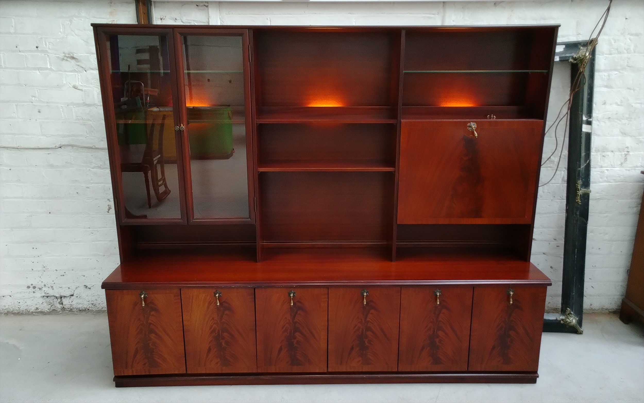 Mid-century Meredew modular display unit with glazed cabinet doors, open shelving, drop-down cocktail compartment, integrated lighting, and a long cupboard base